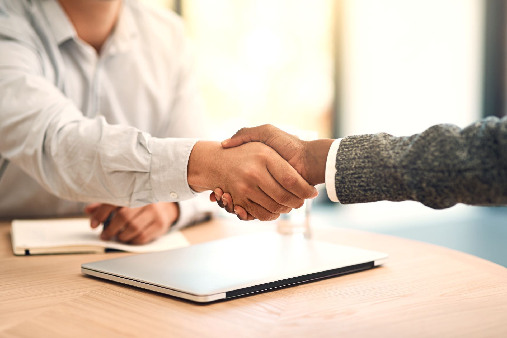 A man and a woman are shaking hands at a table.