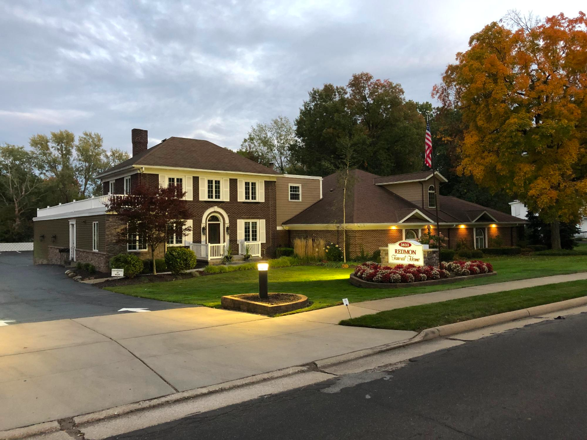A large house with a sign in front of it is lit up at night.