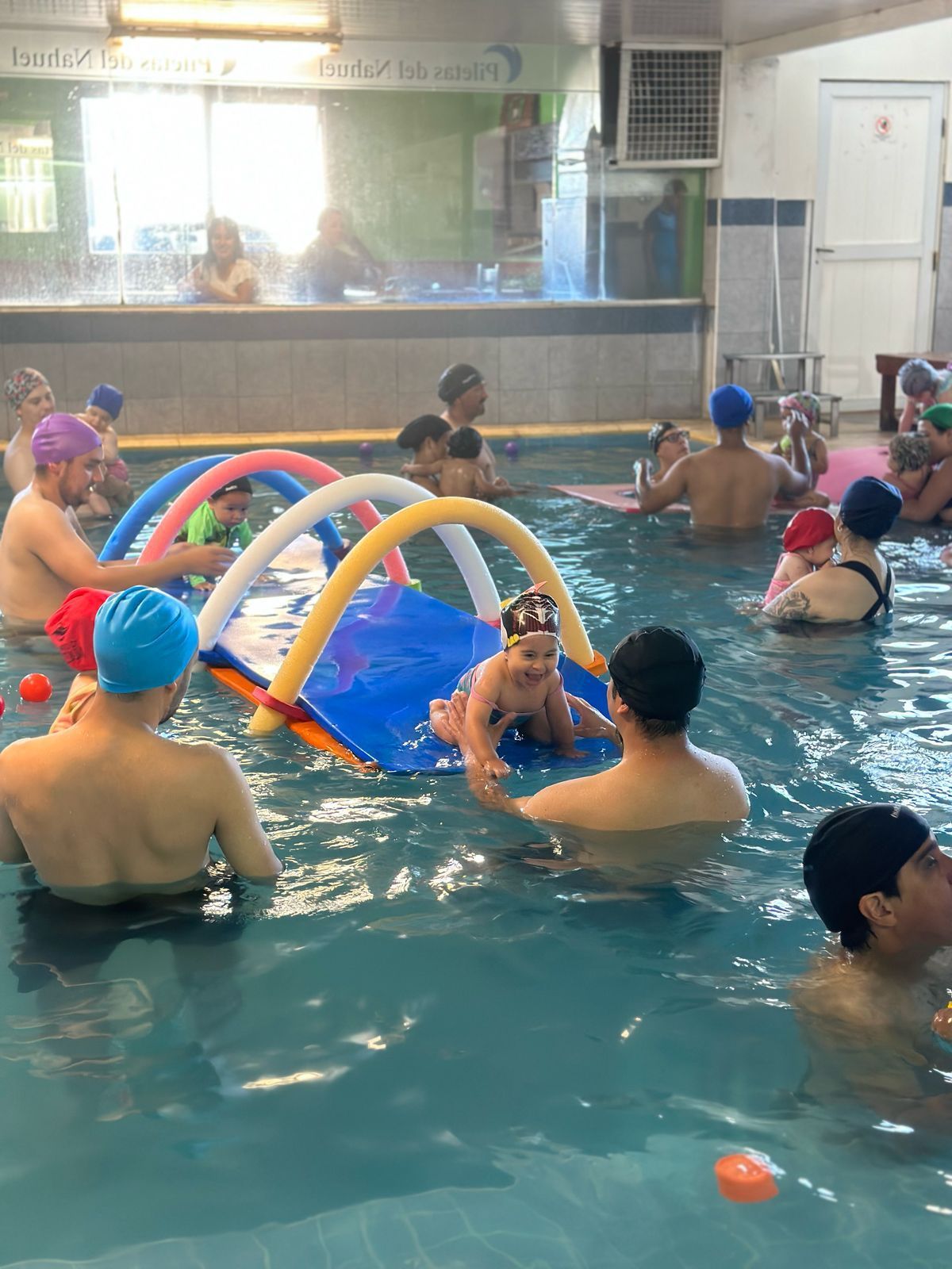Un grupo de personas está nadando en una piscina con fideos de espuma.