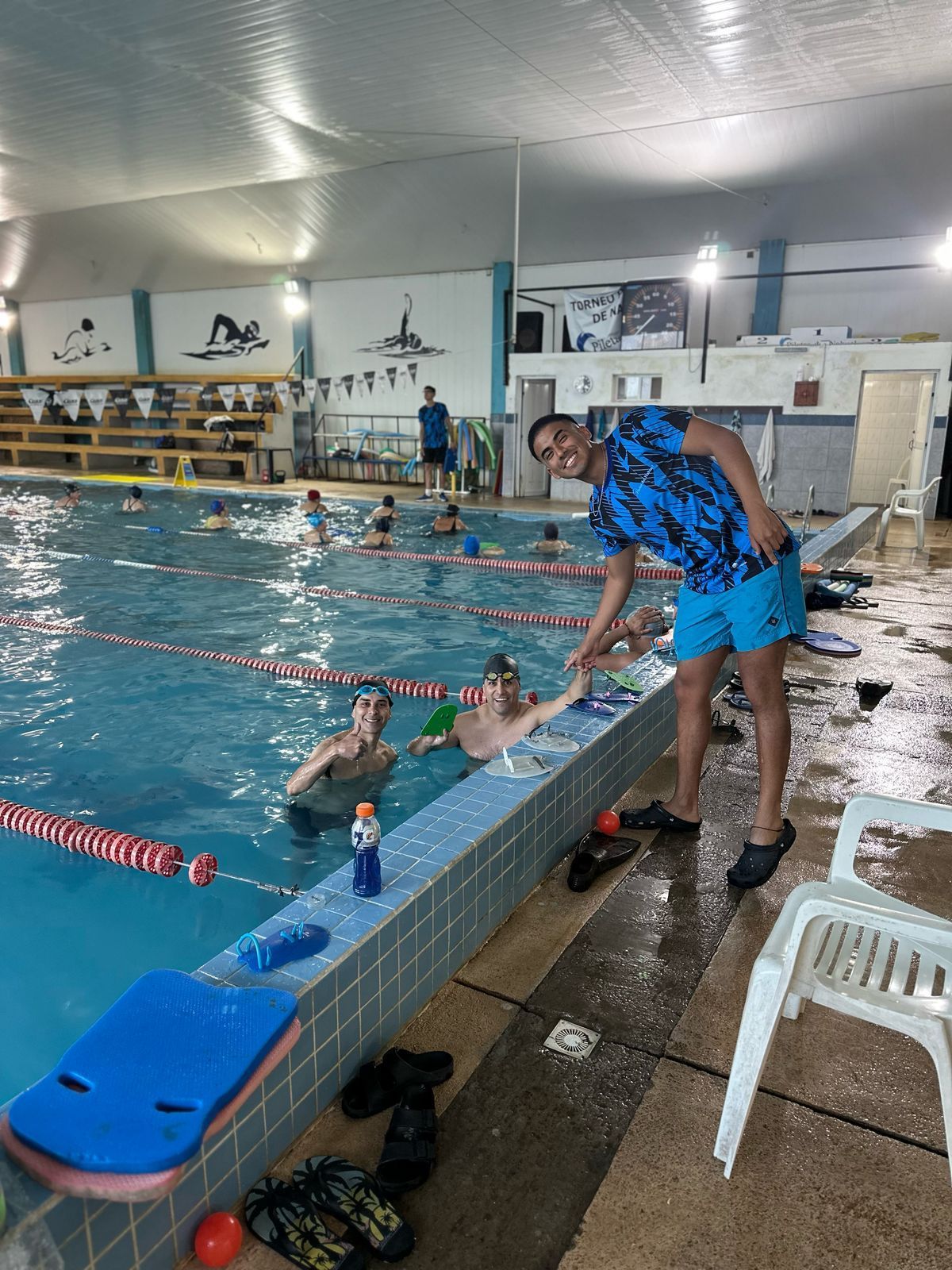 Un grupo de personas está nadando en una gran piscina cubierta.