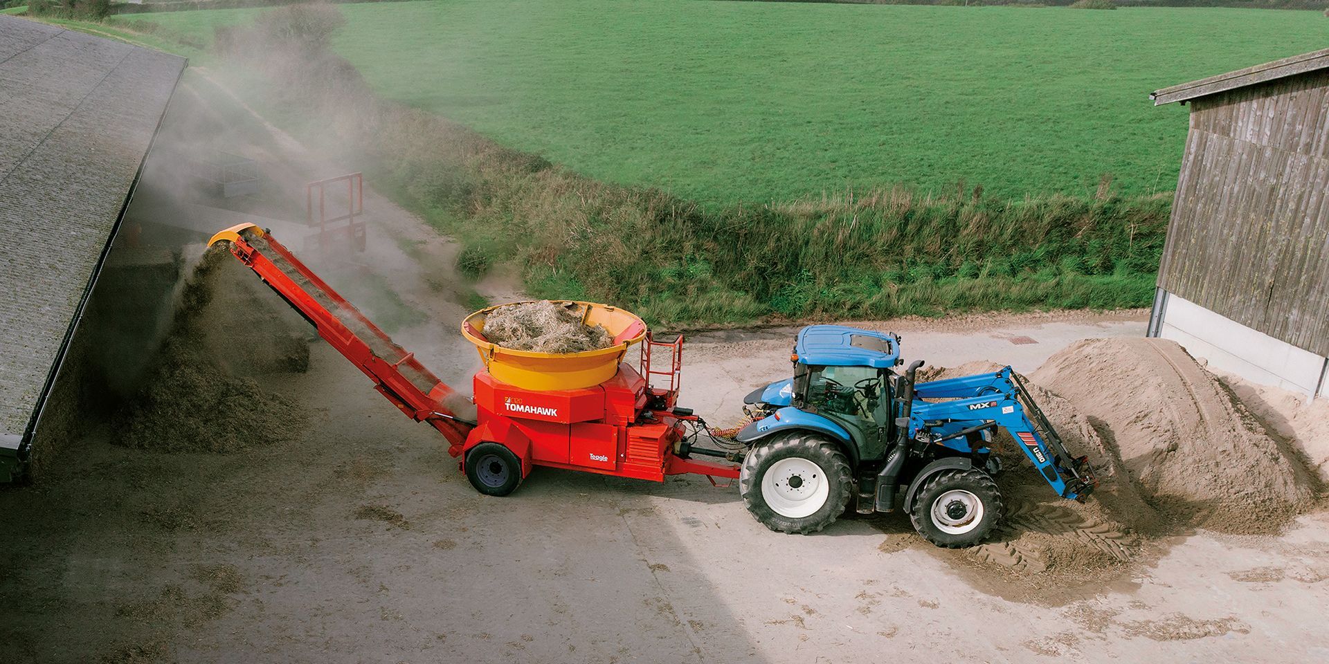 A red and yellow tractor is parked in a barn.