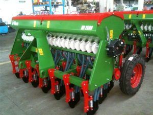 A green and red tractor is sitting on the ground in a warehouse.