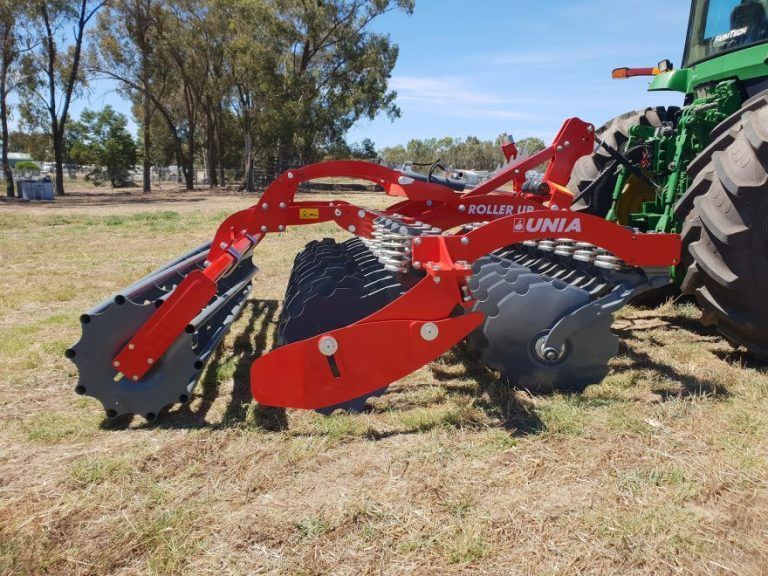 A unia disc tiller is parked in a grassy field
