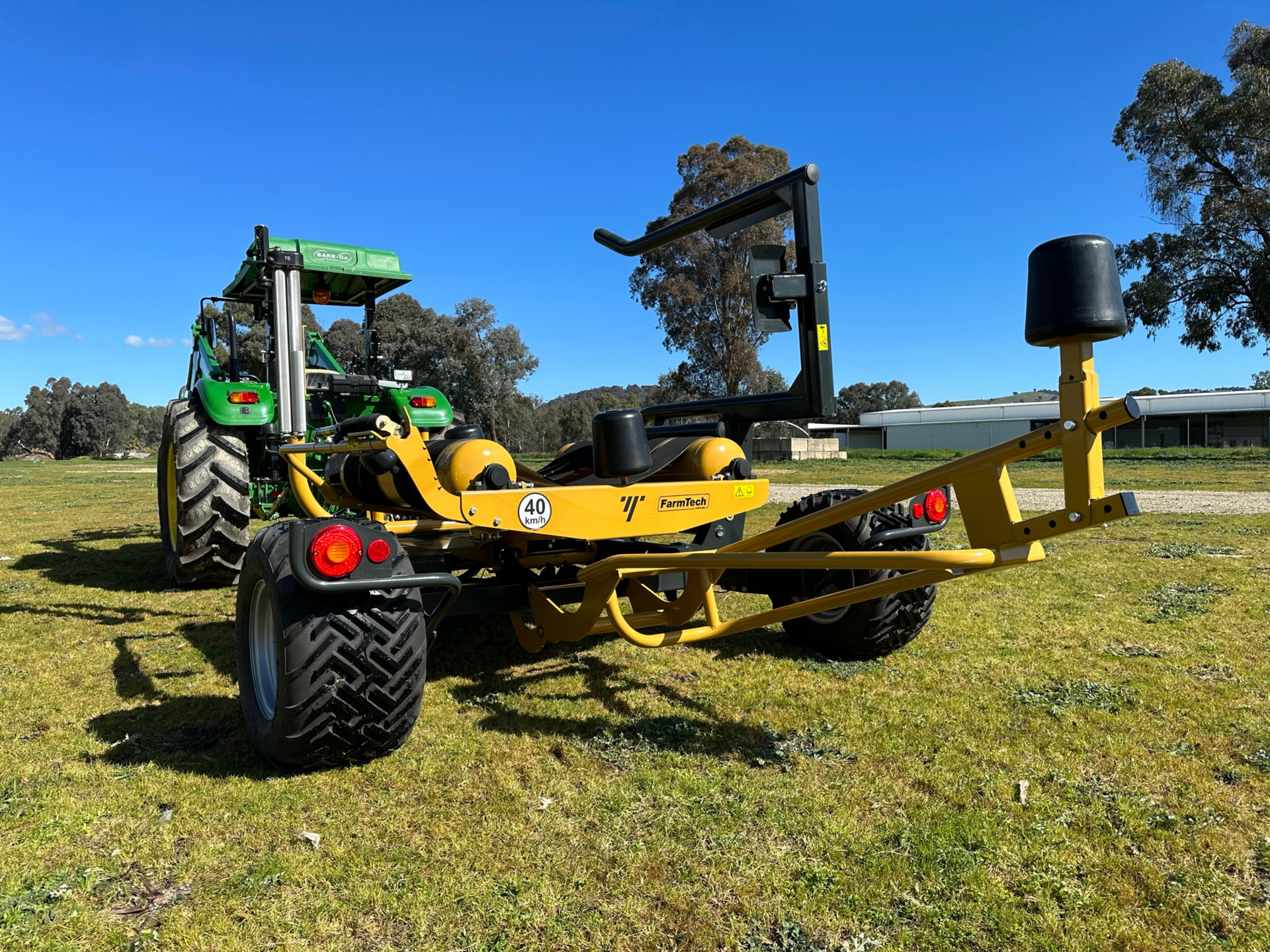 A yellow tractor is parked next to a green tractor in a grassy field