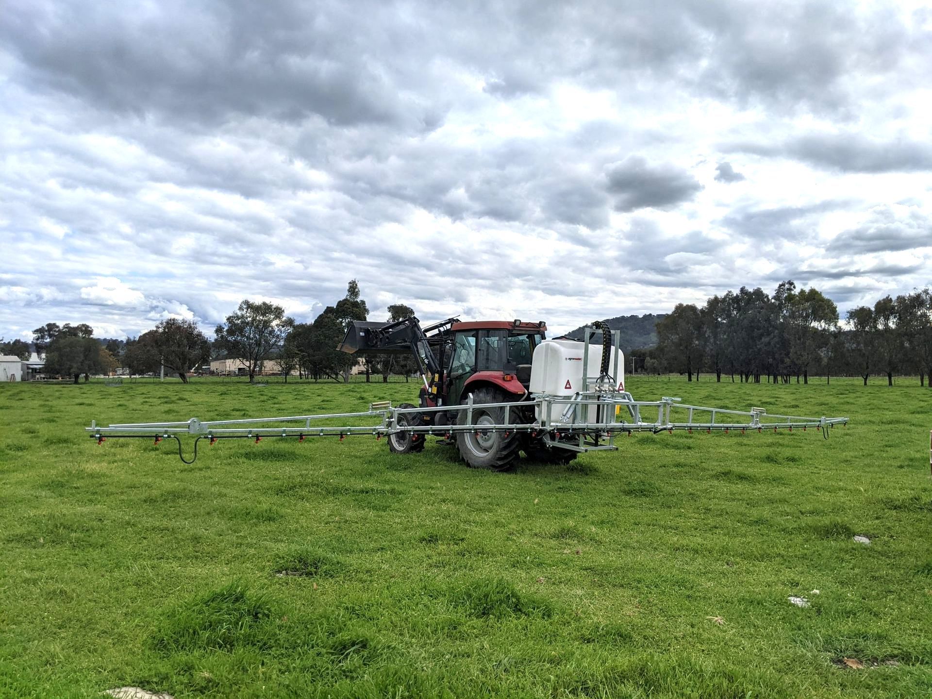 A green and red tractor is parked in a grassy field.