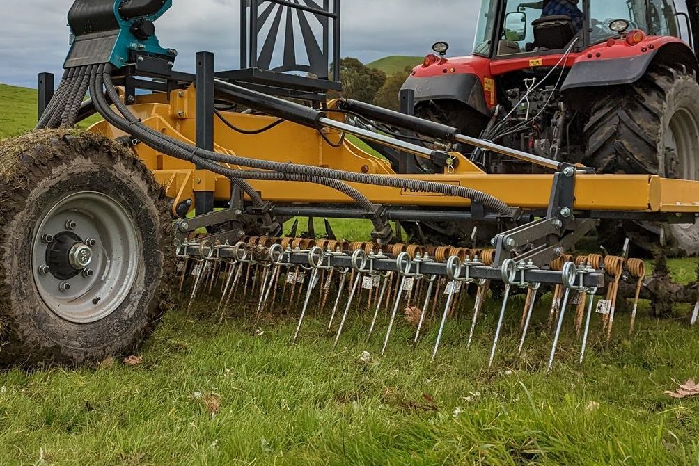 A tractor is aerating a field with a machine attached to it.