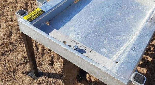 A metal table is sitting on top of a dirt field.