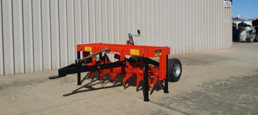A red tractor is parked in front of a white building.