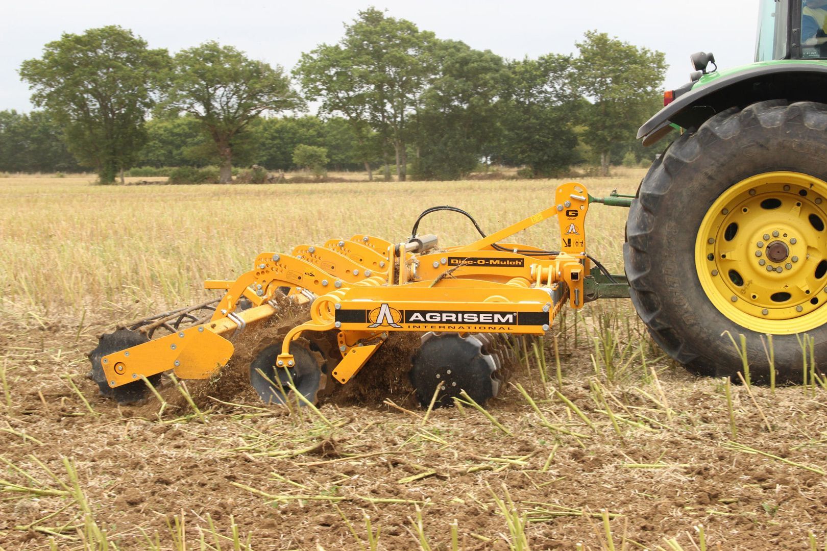 A yellow and black tractor is plowing a field.