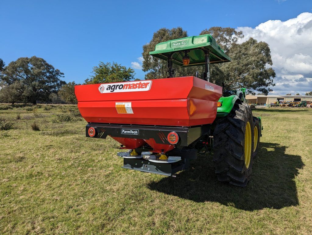 A green and red tractor is parked in a grassy field.