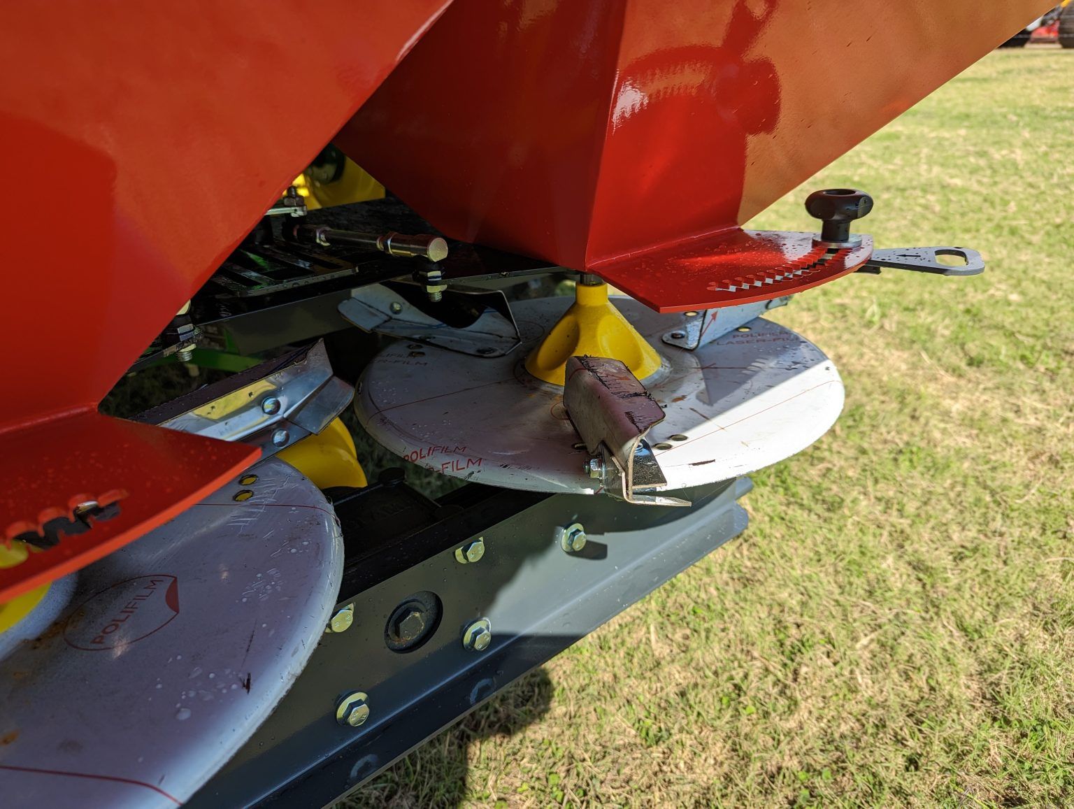 A red and white tractor is parked in a grassy field.