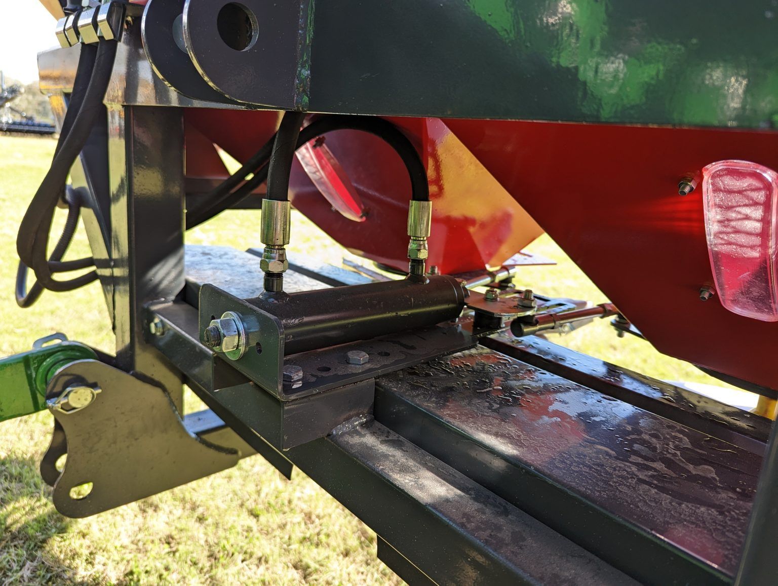 A red and green tractor is parked in a grassy field.