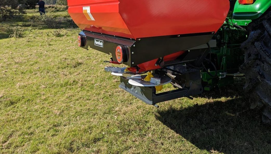 A green and red tractor is parked in a grassy field.