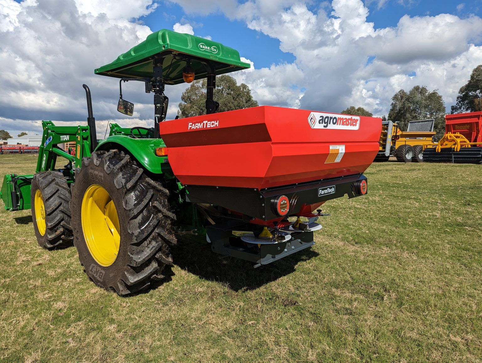A green and red tractor is parked in a grassy field.