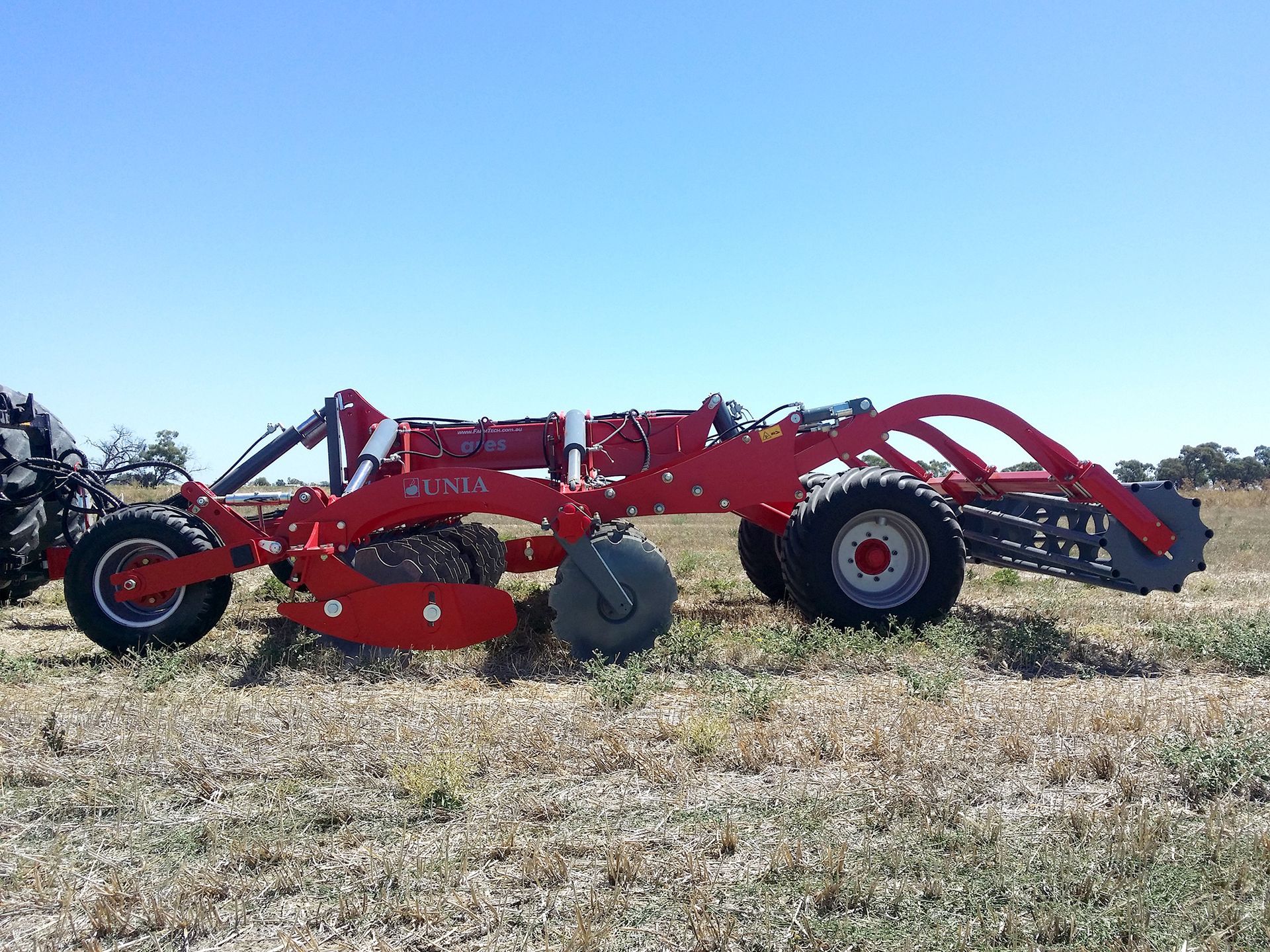 A red tractor is parked in the middle of a field.