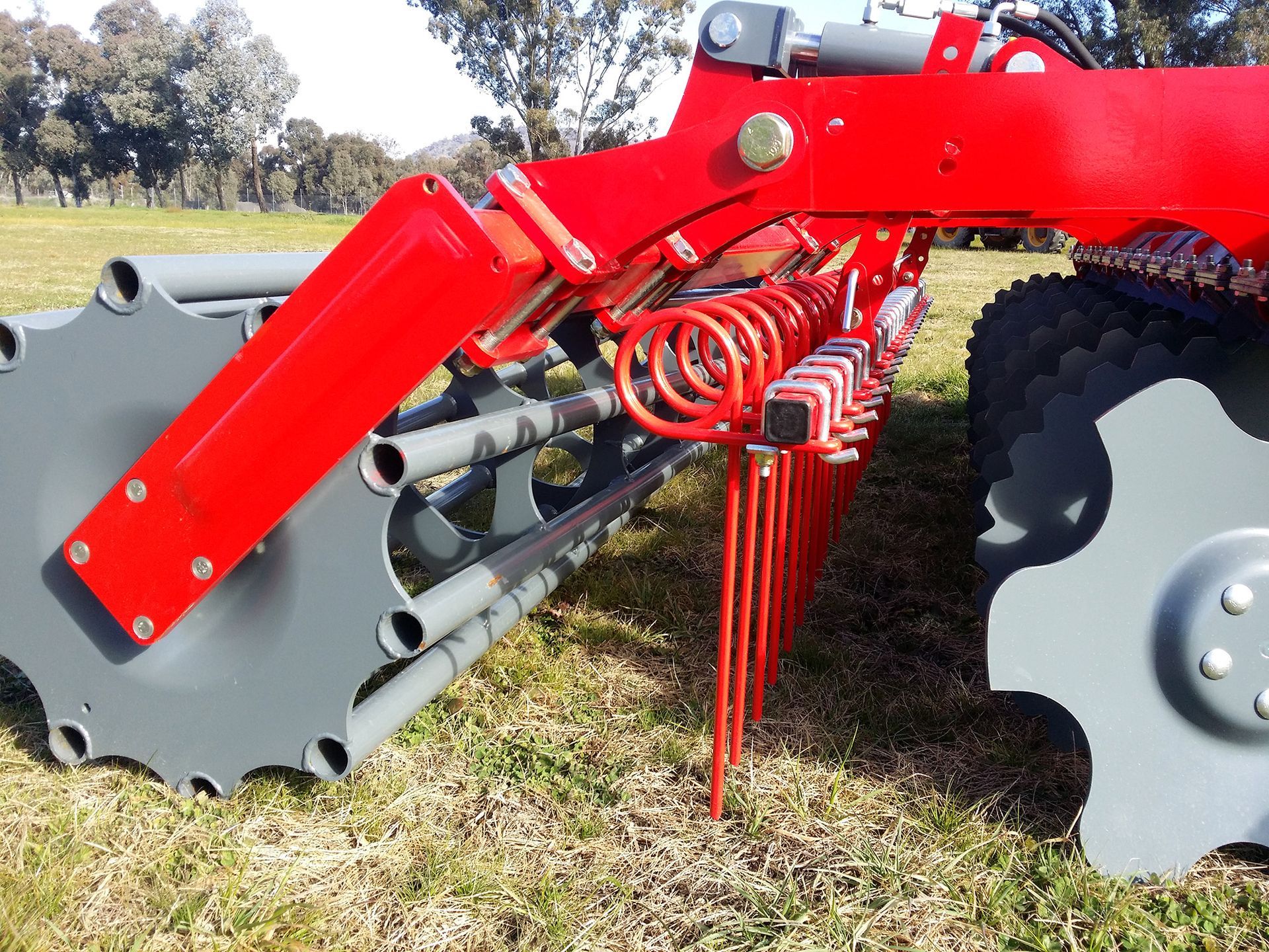 A red and gray tractor is parked in a grassy field