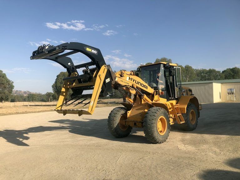 A yellow hyundai tractor is parked on a dirt road.