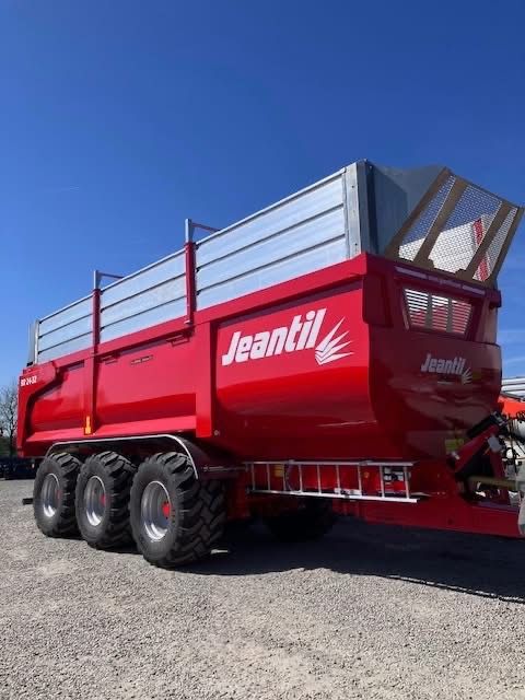 A yellow trailer is attached to a tractor in a dirt field.