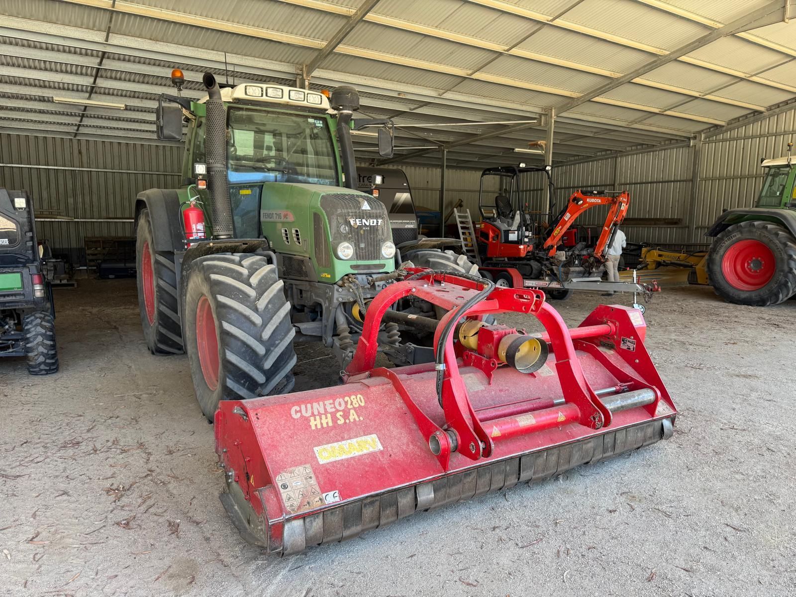 A green and red tractor is parked in a field