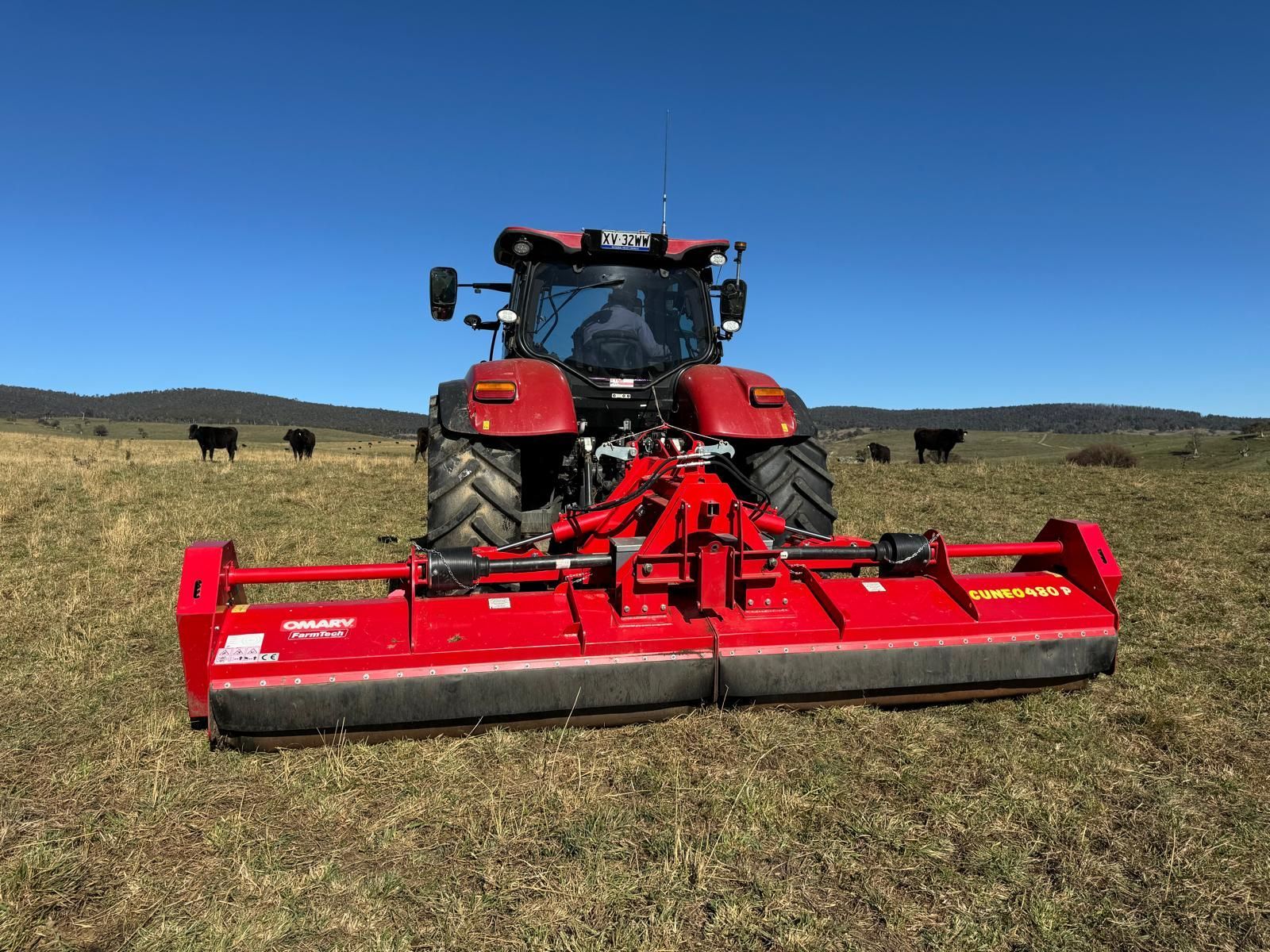 A green and red tractor is parked in a field