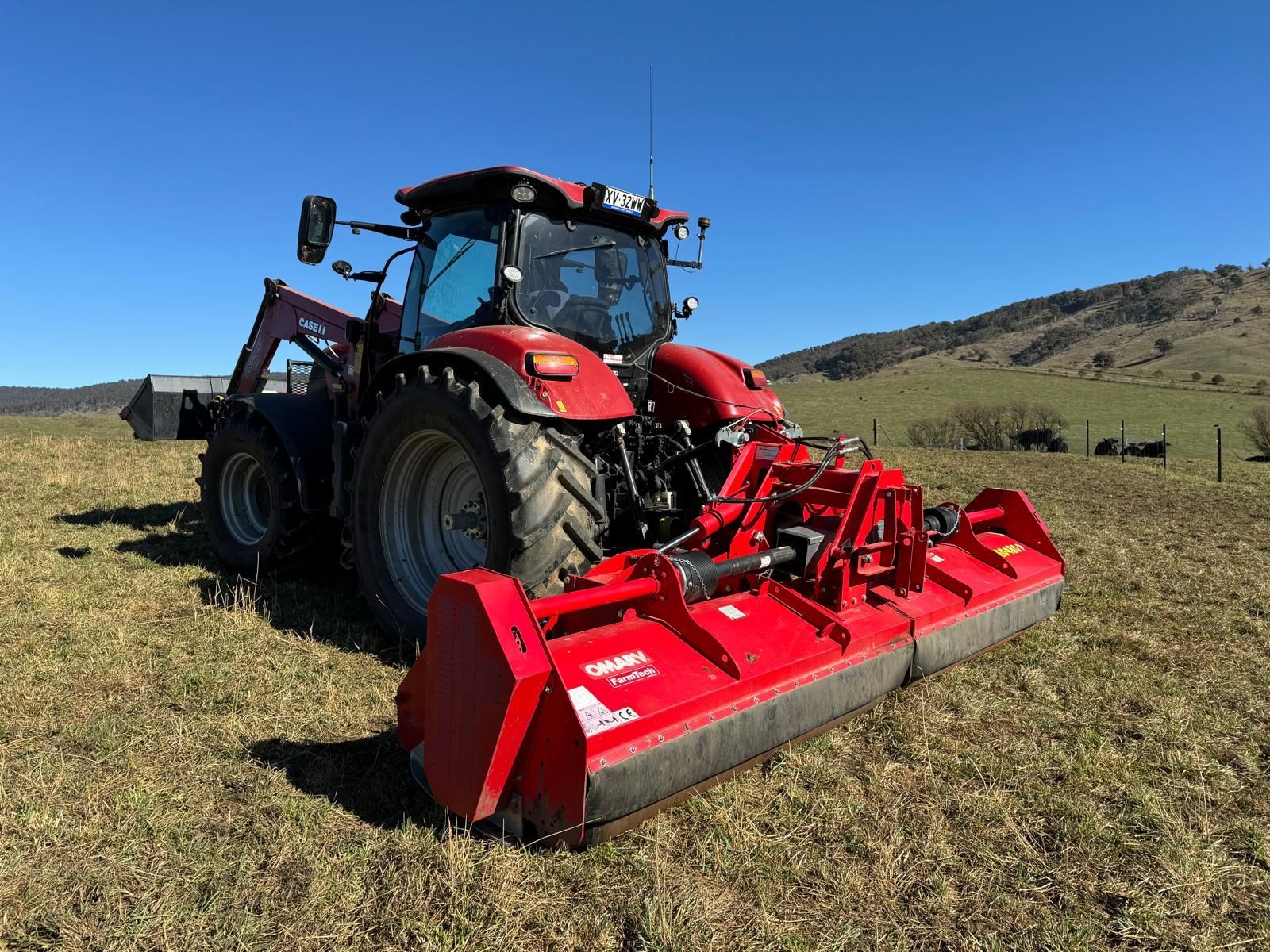 A green and red tractor is parked in a field