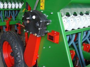 A close up of a green and red machine with a red wheel.