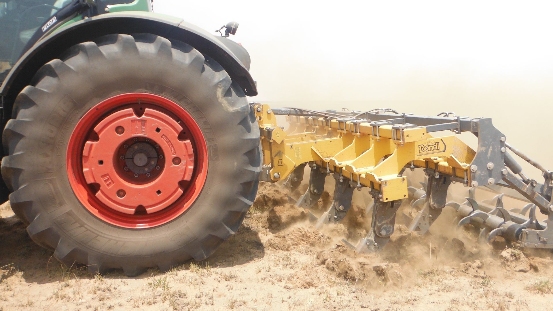 A tractor is plowing a field with a plow attached to it.