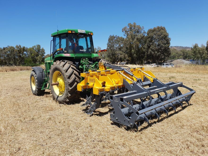 A john deere tractor is parked in a dry field.