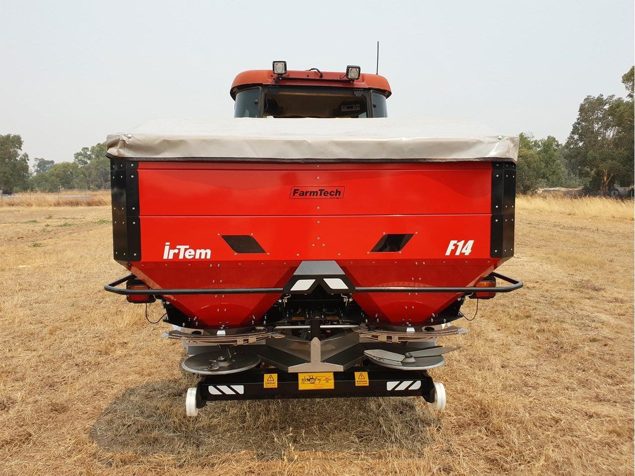 A tractor with a fertilizer spreader attached to it