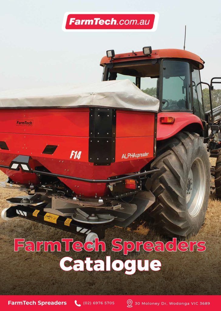 A red tractor with a spreader attached to it is sitting in a field.