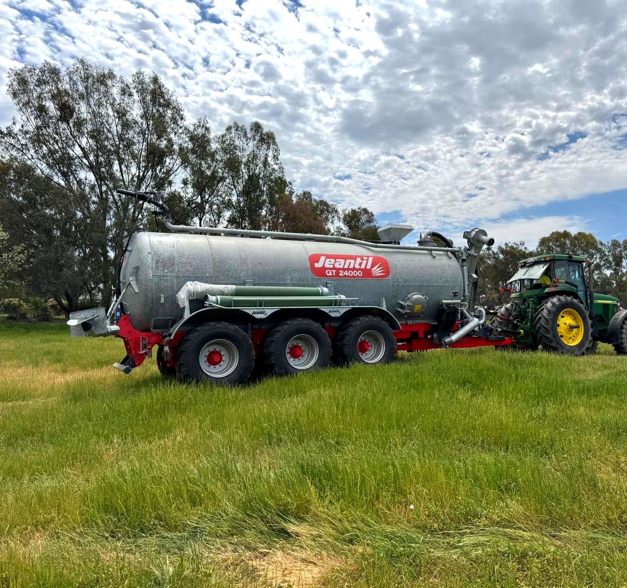 A large tanker truck is parked in a grassy field.