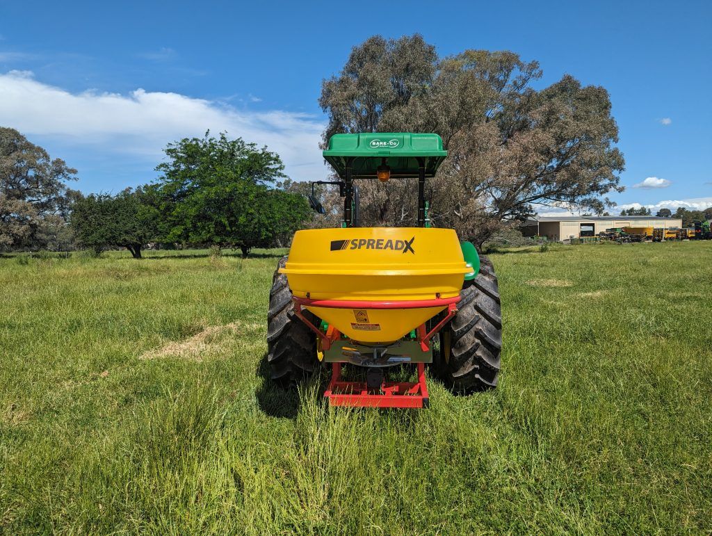 A yellow and green tractor is sitting in a grassy field.