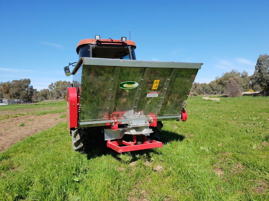 A red tractor is parked in a grassy field.
