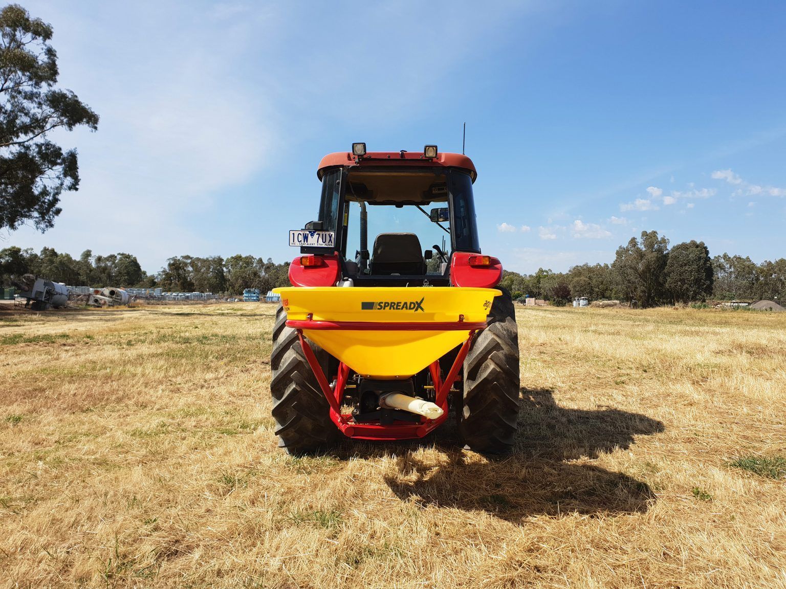 A red and yellow tractor is parked in a field