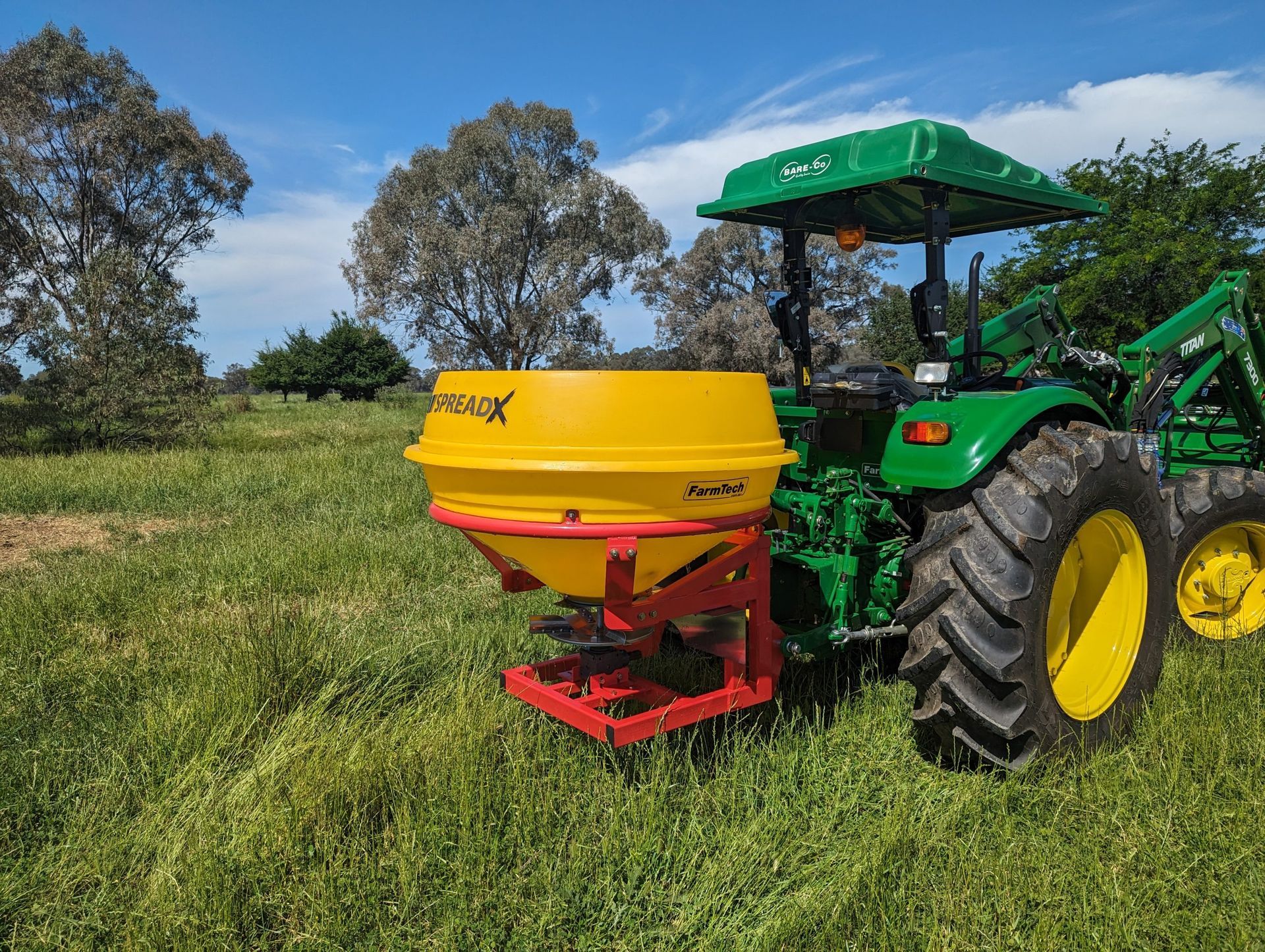A green and yellow tractor is sitting in a grassy field.