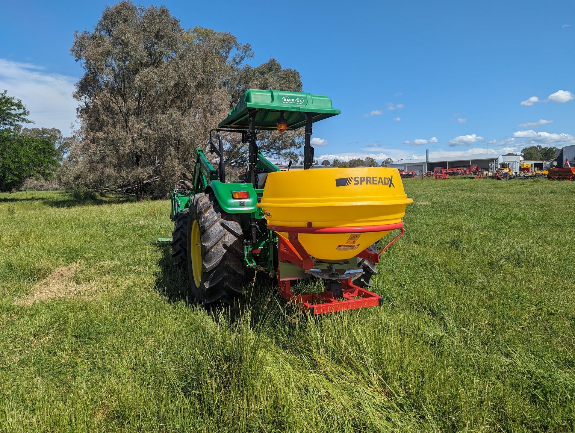A green and yellow tractor is sitting in a grassy field.