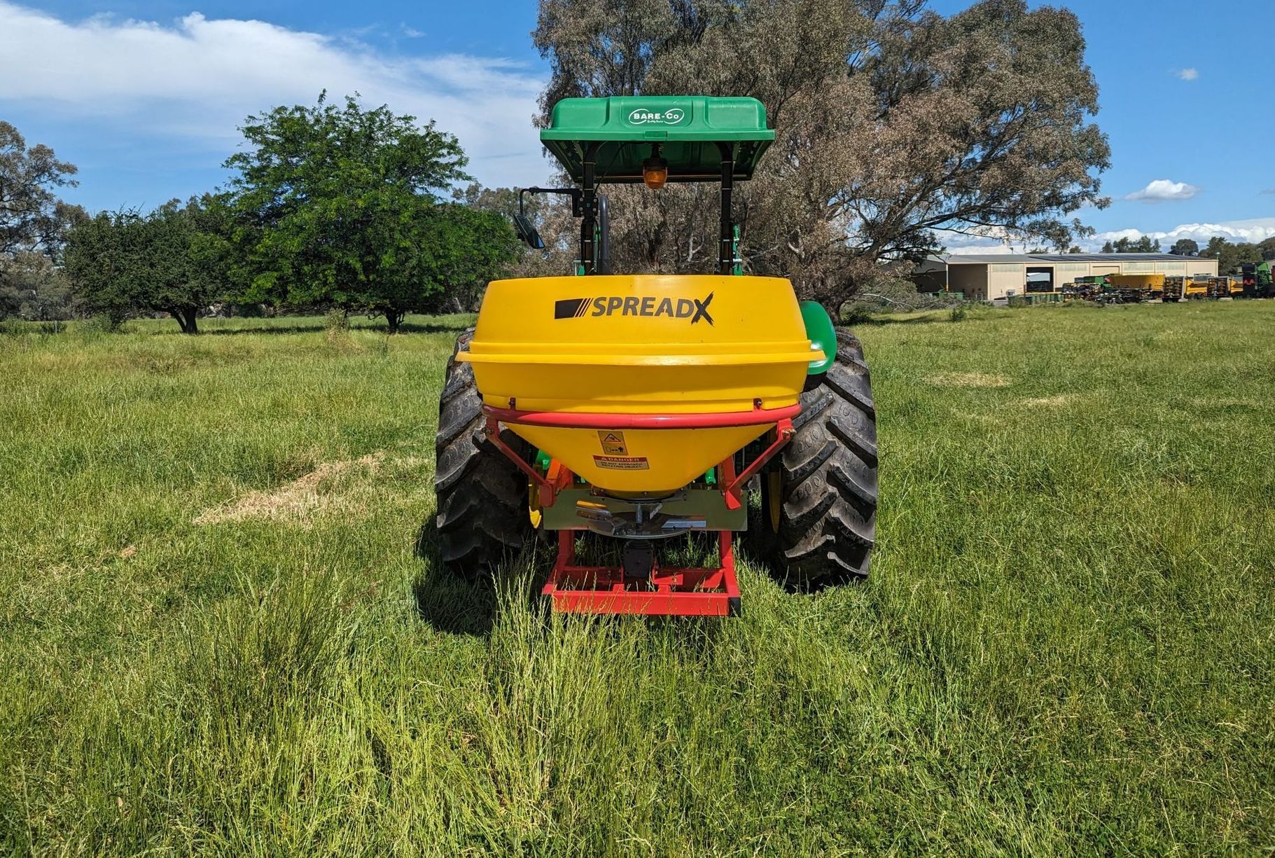 A yellow and green tractor is sitting in a grassy field.