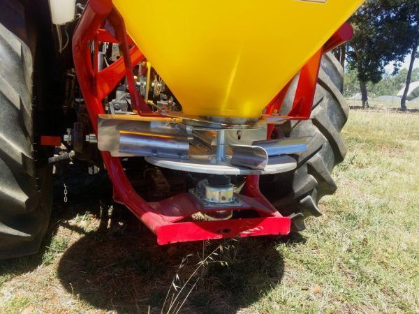 A yellow and red tractor with a fertilizer spreader attached to it