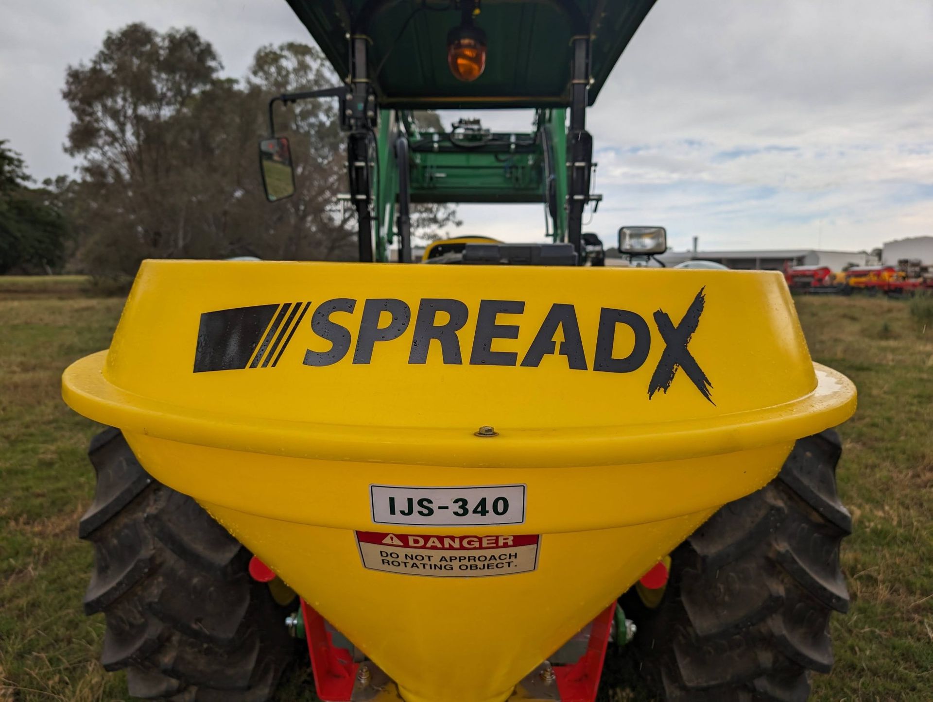 A yellow spreadx tractor is parked in a field