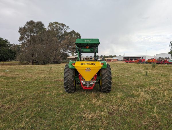 A green and yellow tractor is parked in a grassy field.