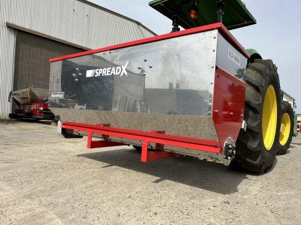A spreader is attached to the back of a tractor