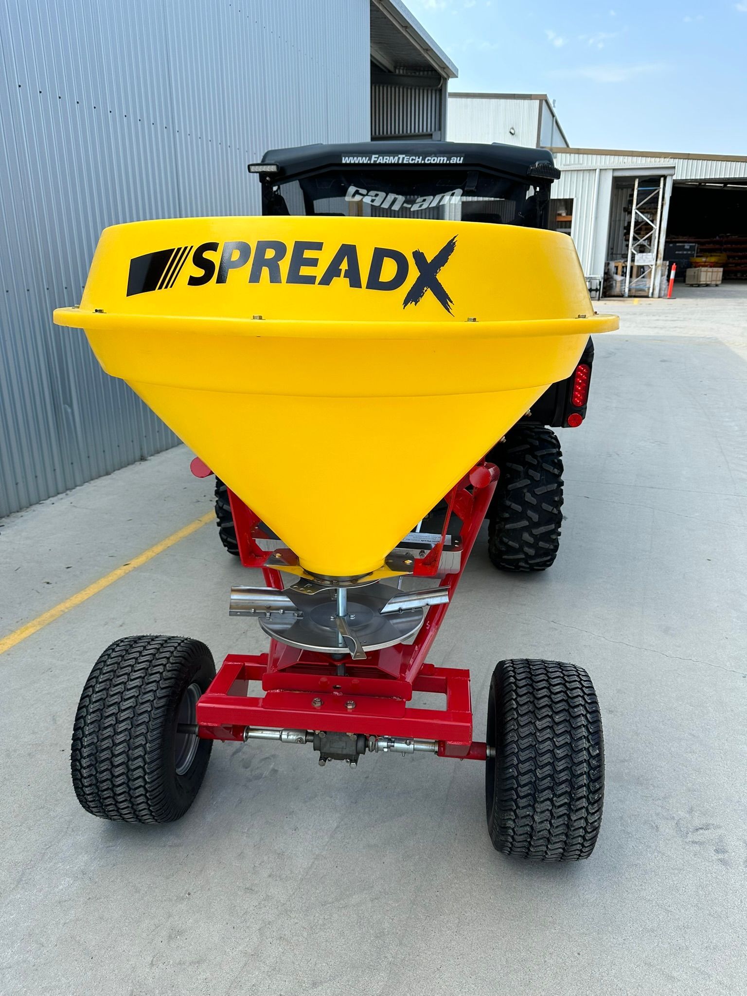 A yellow spreadx vehicle is parked in a parking lot