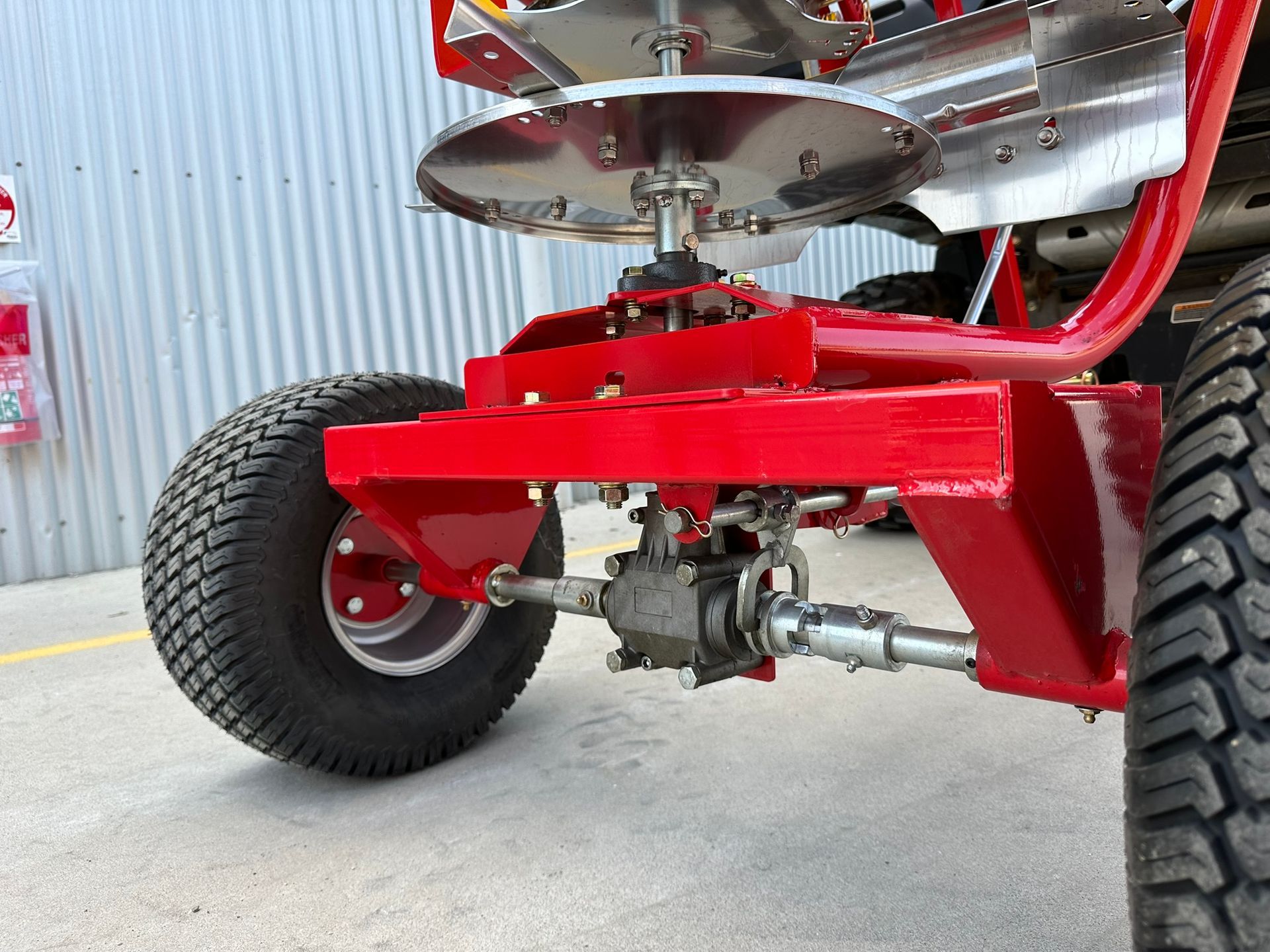 A red lawn mower is parked in front of a building.