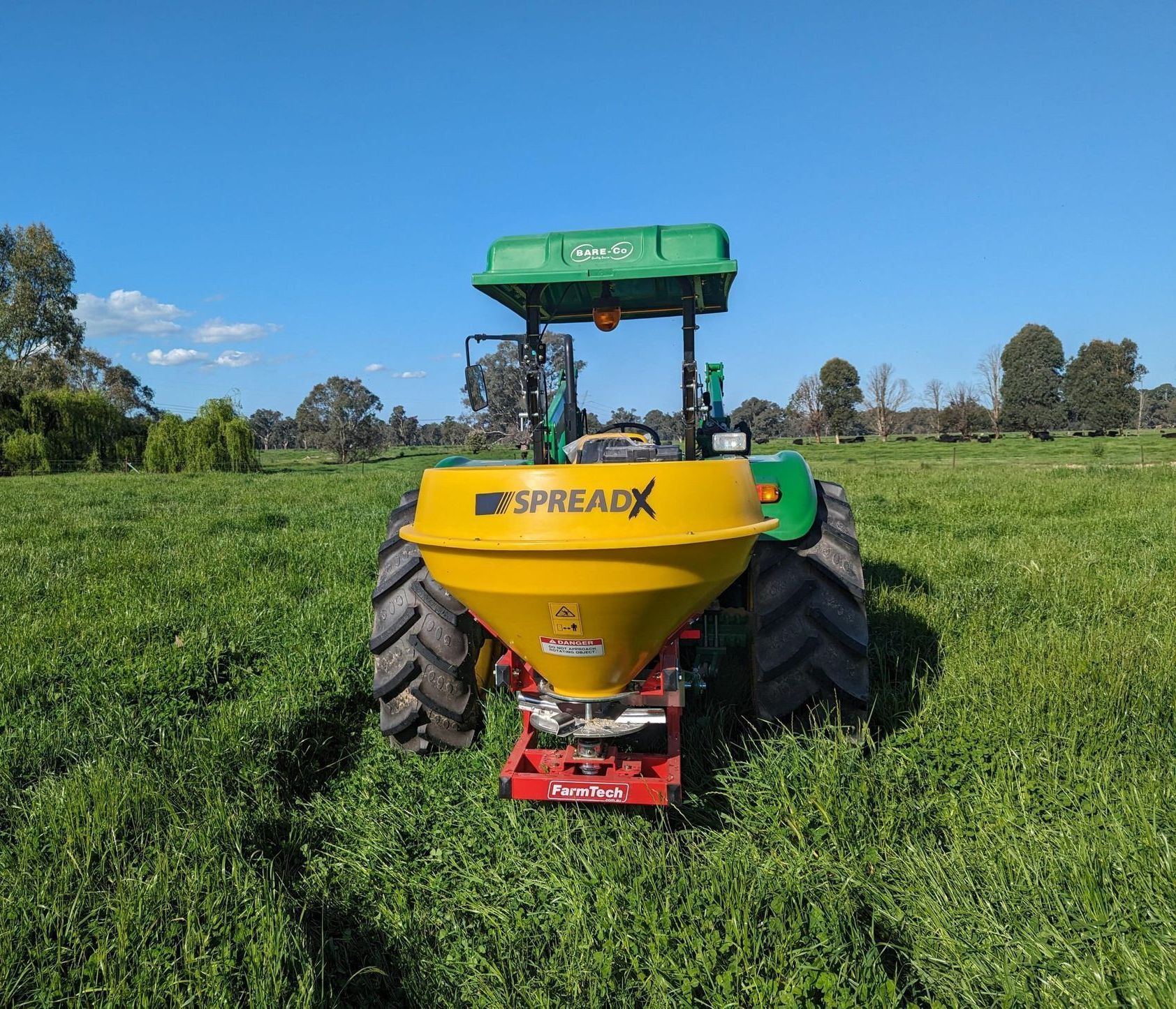 A yellow and green spreadx spreader in a field