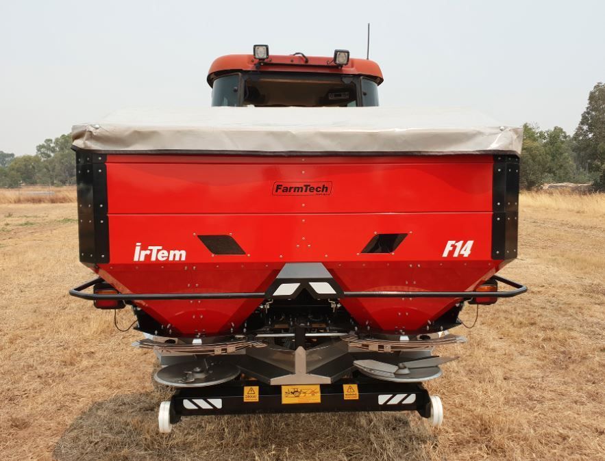 A red irtem f14 spreader is sitting in a field