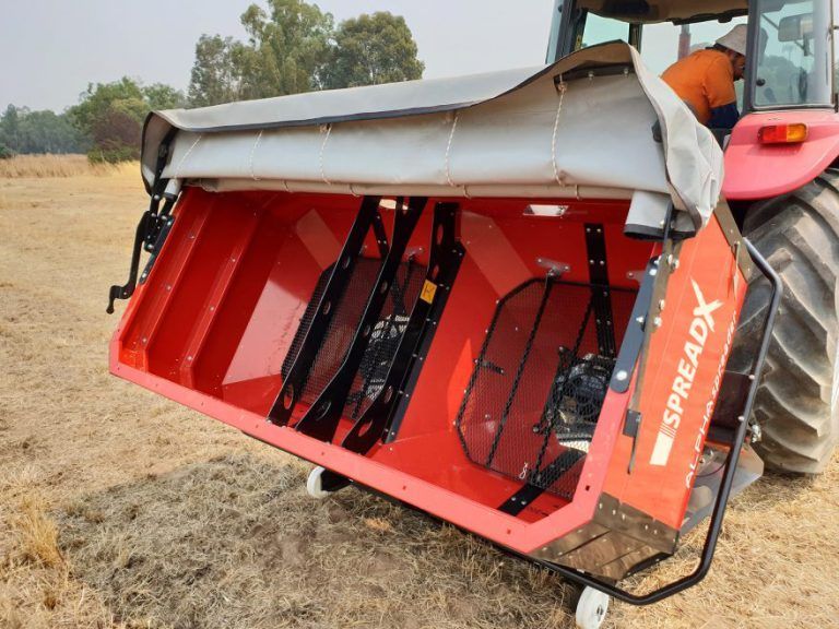 A red irtem fertiliser spreader is parked in a field