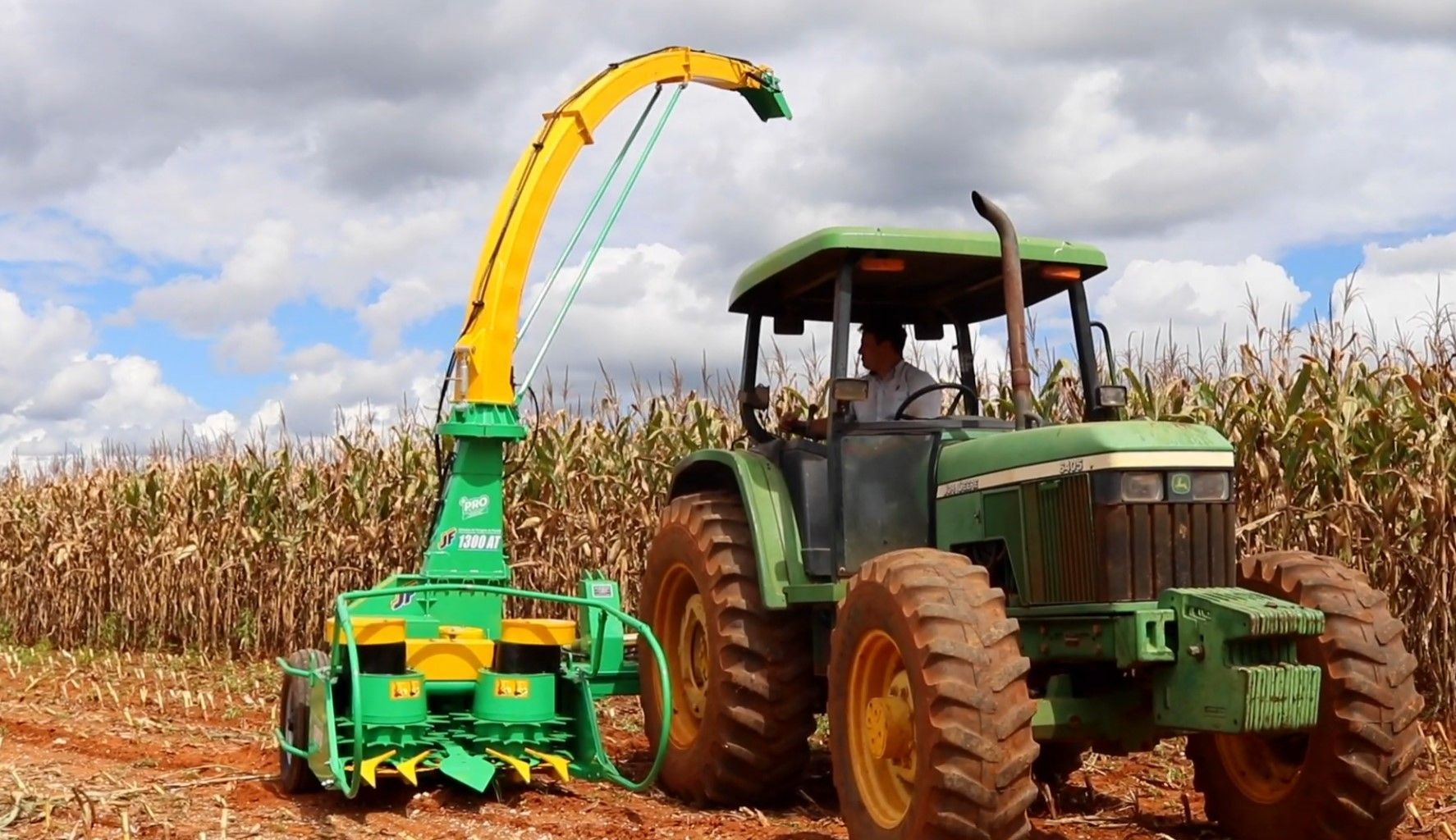 A blue tractor is cutting grass in a field.