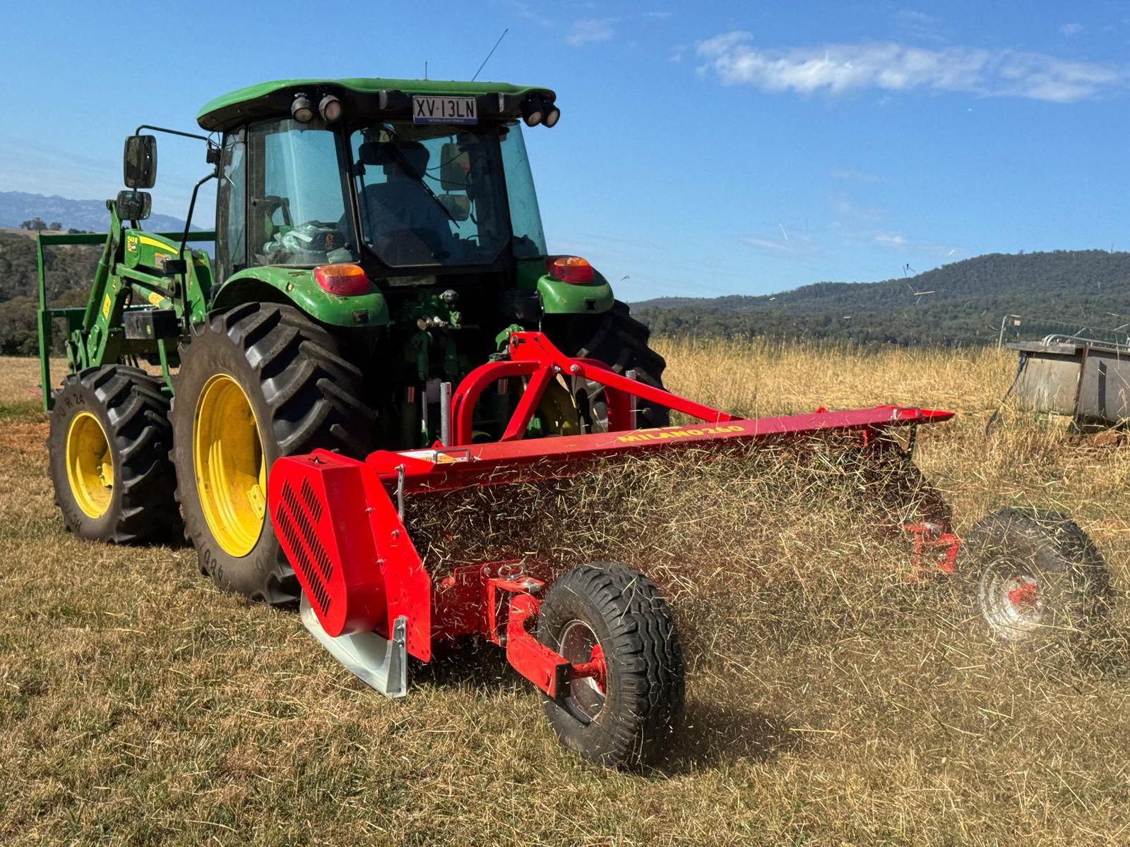 A john deere tractor is cutting grass in a field