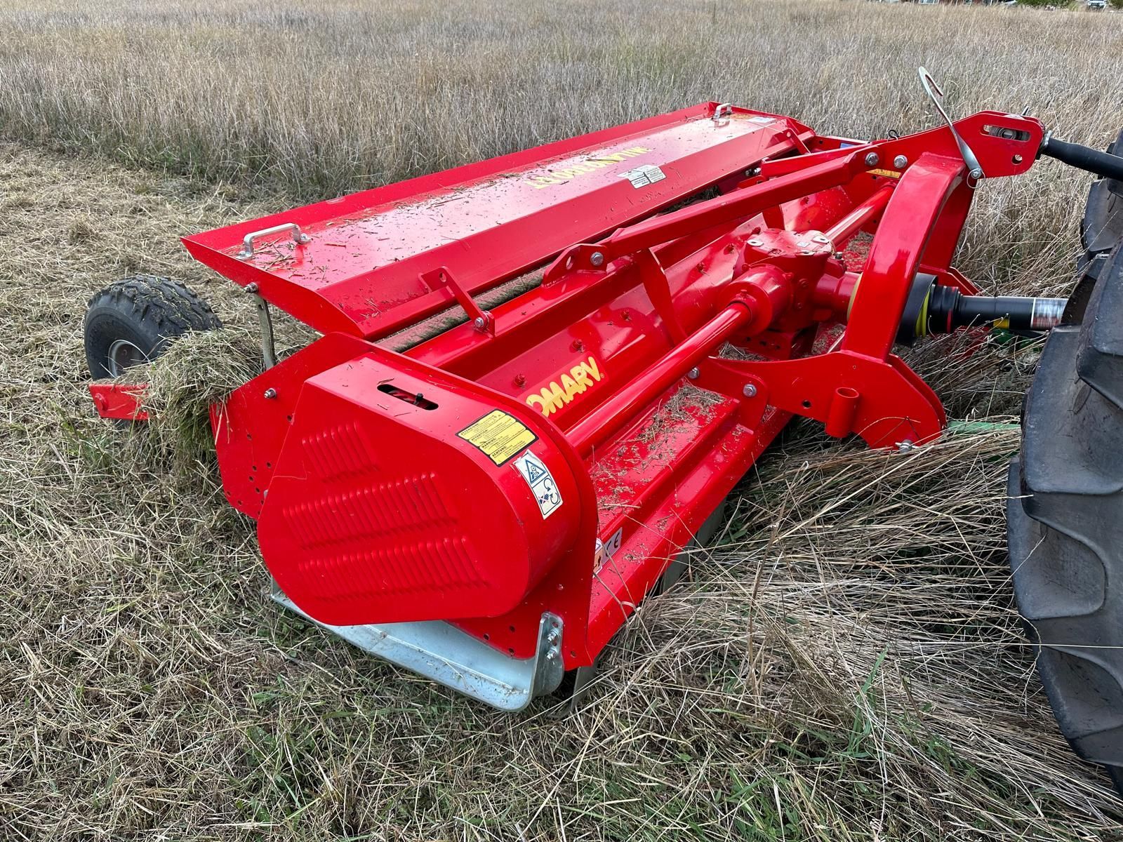 A john deere tractor is cutting grass in a field