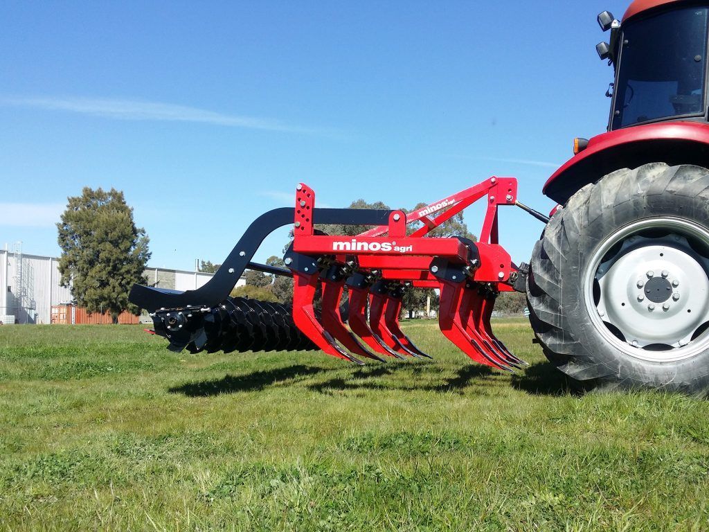 Side view of a yellow disc tiller in a field.